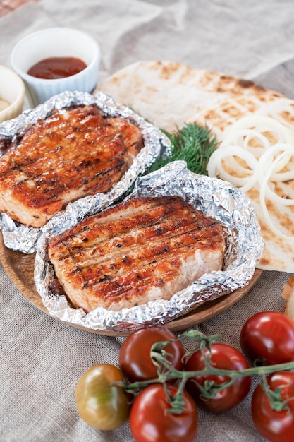 Grilled pork meat in foil with flapjack and vegetables summer rest concept