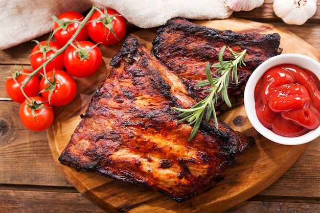 Grilled pork ribs with rosemary on wooden board, top view