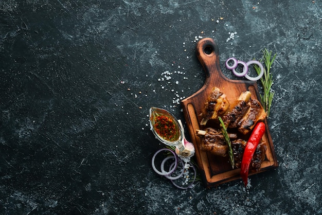 Grilled pork ribs with spices on black stone background Top view Free copy space