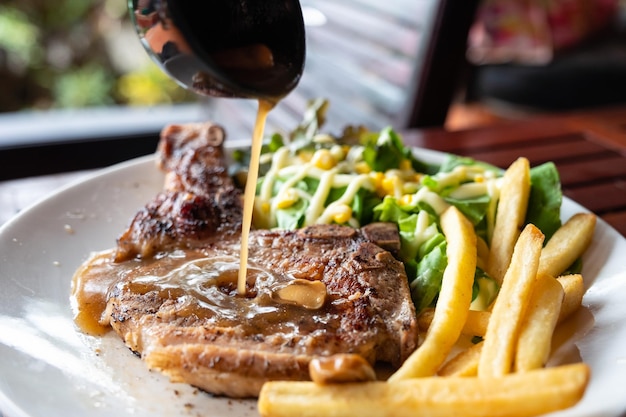 Grilled pork steak with pouring sauce recipe with frenchfries and salad