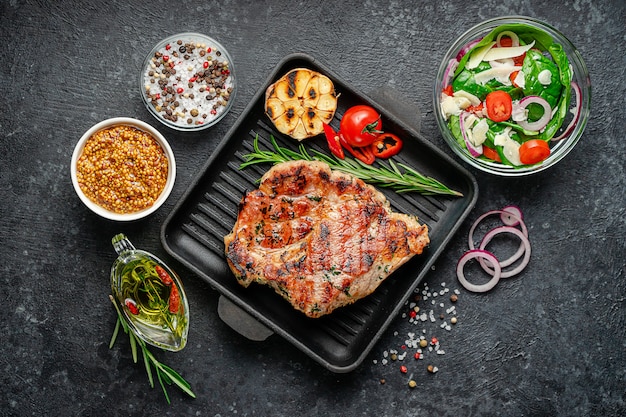 grilled pork steak with spices and fresh salad. Top view