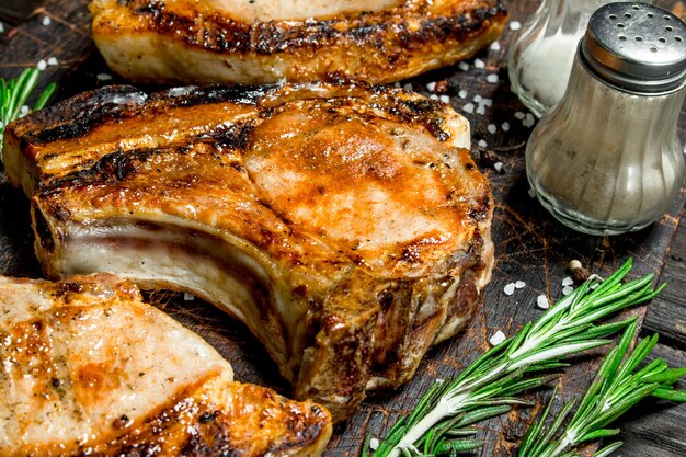 Grilled pork steaks with rosemary and salt on an old board