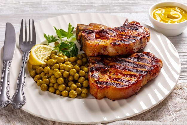 Grilled pork tbone steaks with boiled green peas