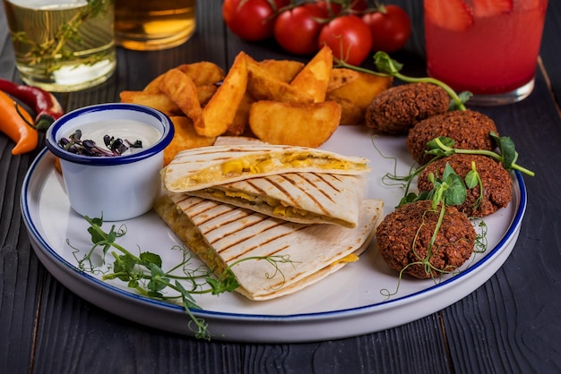 Grilled quesadillas with falafel on black wooden background