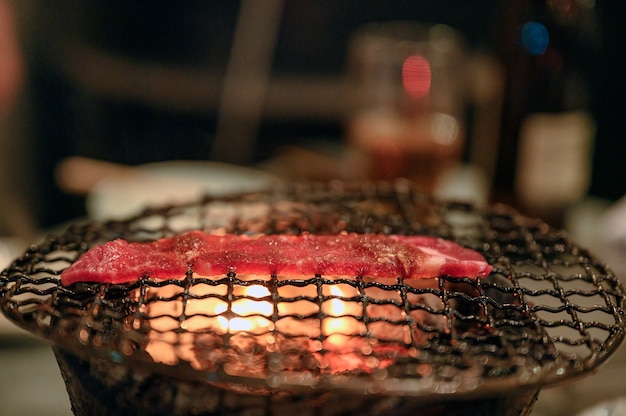 Grilled raw beef slice on flaming charcoal grill