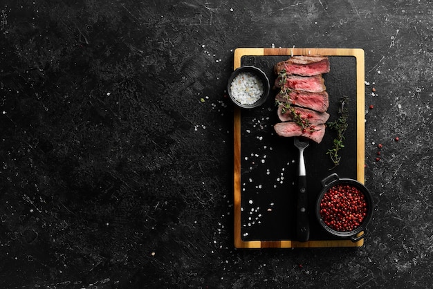 Grilled rib eye steak on a fork herbs and spices Top view with copy space for text Top view with space for copying text