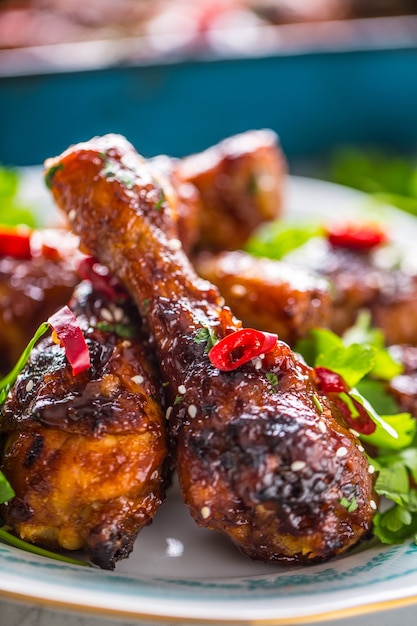 Grilled roasted and barbecue chicken legs on white plate with herb decoration.