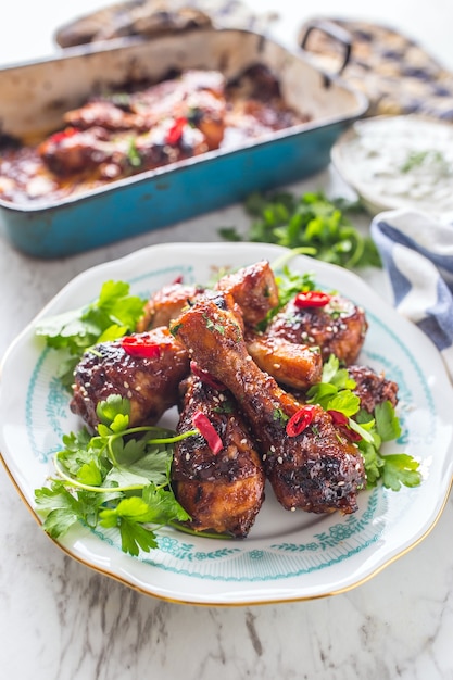 Grilled roasted and barbecue chicken legs on white plate with herb decoration.