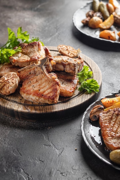 Grilled roasted bbq pork stake served with vegetables on brown table background Party table Vertical