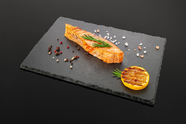 Grilled salmon fillet on a black slate board