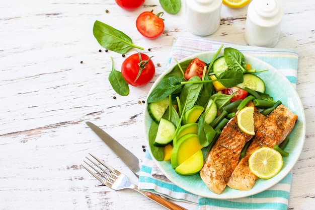 Grilled salmon fillet with spinach cucumber tomato and avocado salad Copy space