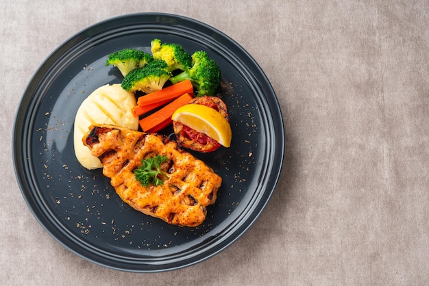 Grilled salmon fillets with mentai sauce and mash potato plating on black plate with negative space