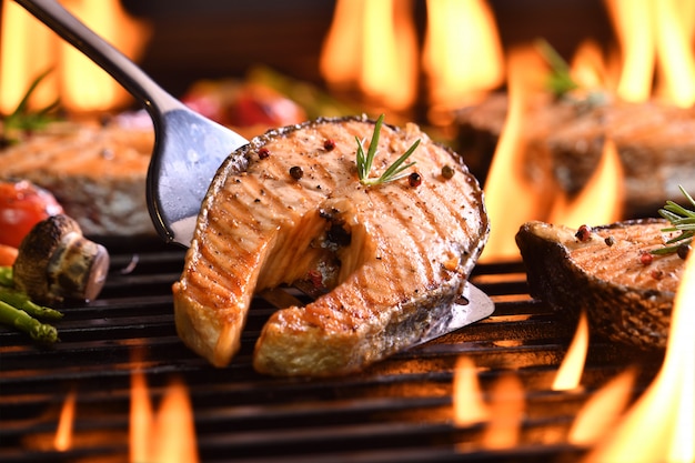 Grilled salmon fish with various vegetables on the flaming grill