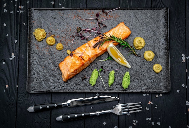 Photo grilled salmon and spices on stone plate top view