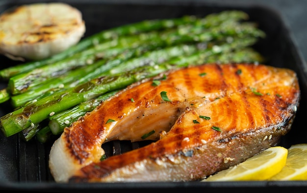 Grilled salmon steak and asparagus on grill pan Close up