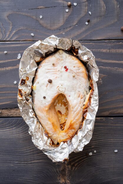 Grilled salmon steak on dark wooden background top view