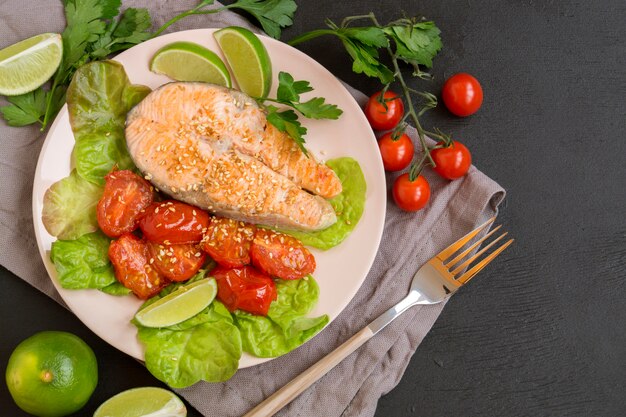 Grilled salmon steak with vegetables. on a dark table.