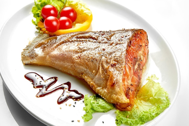 Grilled salmon tail in a white plate White background Selective focus Closeup