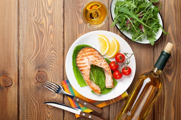 Grilled salmon and white wine on wooden table