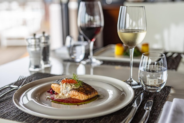 Grilled salmon with vegetables sauce served on white plate elegant table. Gourmet luxury food, wine