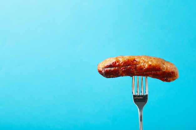 Grilled sausage on a fork with copy space. Top view.