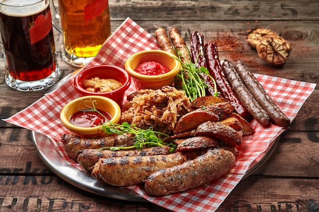 Grilled sausages with potato wedges stewed cabbage and sauces as beer snack