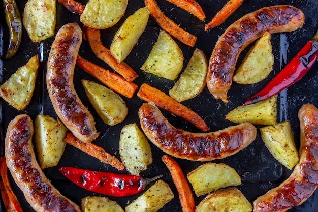 Grilled sausages with potatoes, carrots and chilli. German cuisine.