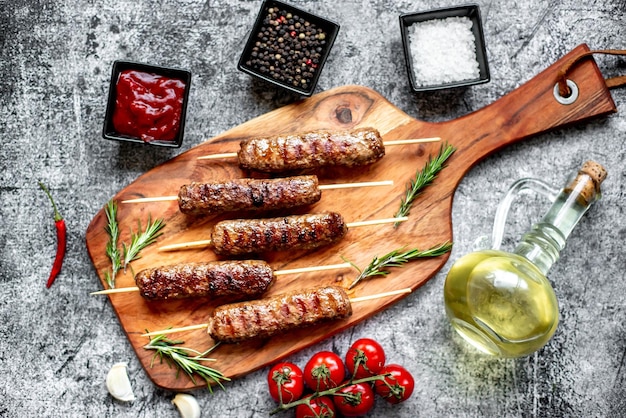 Grilled sausages on a wooden board with herbs and spices