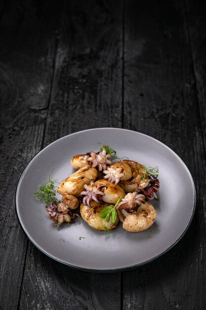 grilled seafood in a gray round plate on a dark wooden table