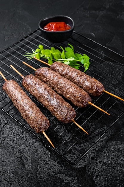 Grilled shish kebab arabic kofta kofte kebab from mince lamb and beef meat on Skewer Black background Top view