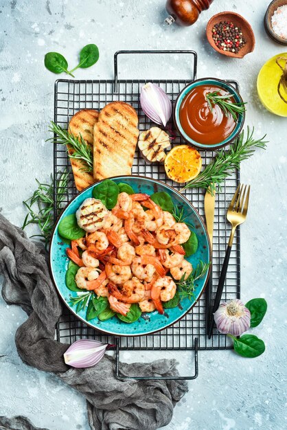 Grilled shrimp served with lemon and sauce Seafood on a plate On a gray stone background Top view