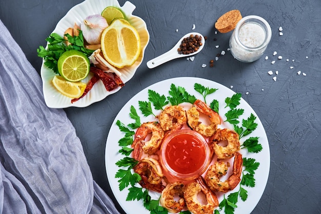 Grilled shrimps on white plate with fresh parsley spices and lemon fried prawns with sauce in jar top view