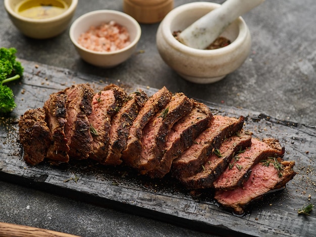 Grilled sliced beef steak on cutting board over grey table Beef tenderloin steak Filet Mignon recipe