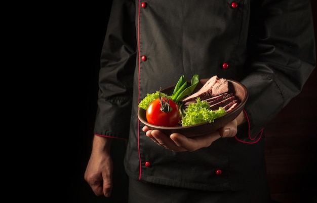 Grilled and sliced beef steak with grilled vegetables served on plate presentation in chef hands