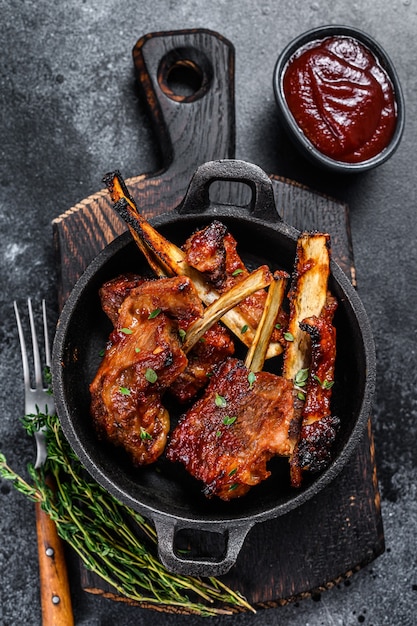 Grilled sliced beef or veal short spare loin ribs in a pan. Black background. Top view.