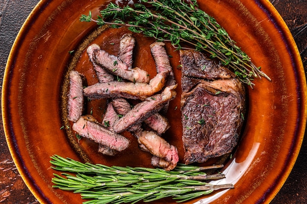 Grilled sliced rib eye or ribeye beef meat steak on a rustic plate.