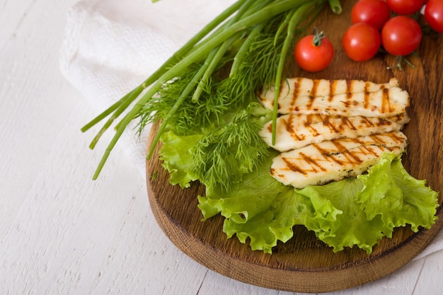 Grilled slices of homemade halloumi cheese with green salad fresh herbs and organic tomatoes