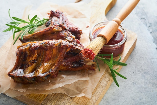 Grilled and smoked pork ribs with barbeque sauce on an old vintage wooden cutting board on old wooden table background Tasty snack to beer American food concept Top view