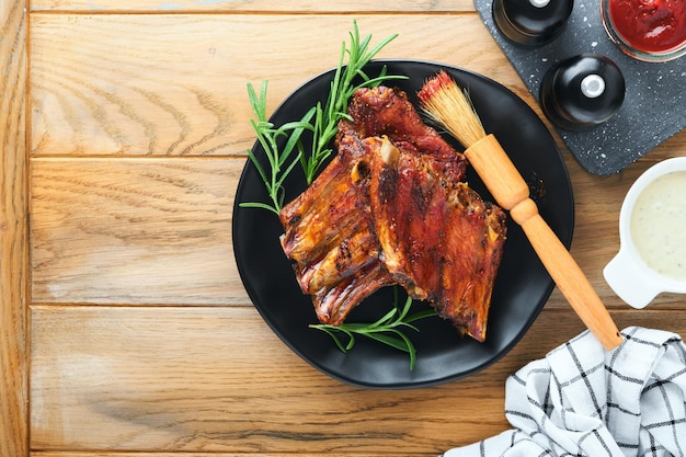 Grilled and smoked pork ribs with barbeque sauce on an old vintage wooden cutting board on old wooden table background Tasty snack to beer American food concept Top view