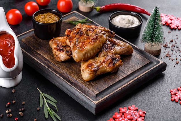 Grilled spicy chicken wings on a dark background with spices and herbs