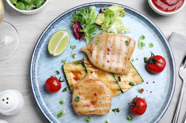 Grilled squid tubes served on white wooden table flat lay