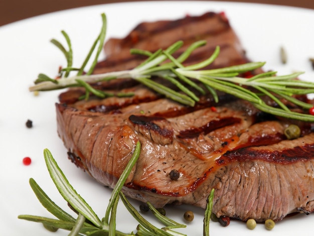 Grilled steak on plate with spices and rosemary closeup