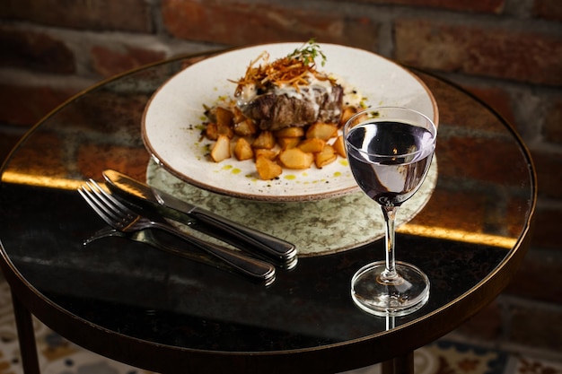 Grilled steak with baked golden potatoes served with crispy onion on top on a brick background Delicious Recipe