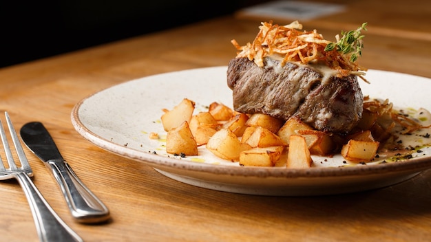 Grilled steak with baked golden potatoes served with crispy onion on top on a brick background Delicious Recipe