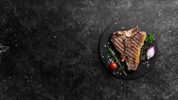 Grilled tbone beef steak Steak on a black plate Top view On a black stone background