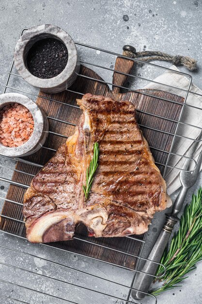 Grilled tbone porterhouse beef meat Steak on a grill with spices Gray background Top view