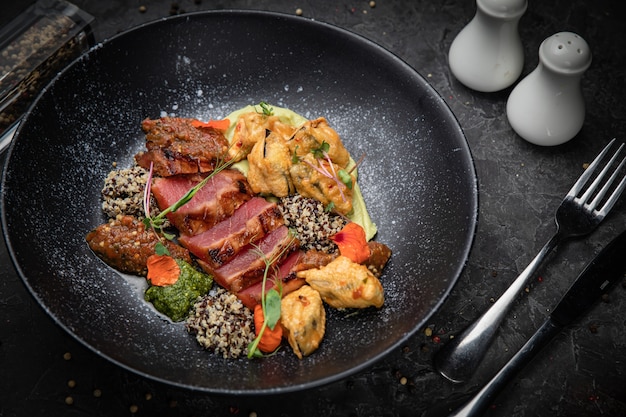 Grilled tuna fish  In a dark plate on a dark concrete table