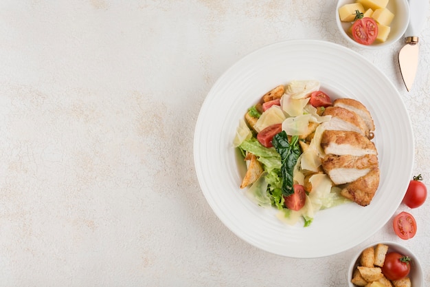 Grilled turkey fillet with fresh salad and vegetables on a green plate on a light background. Top view with a copy space for the text. Food from the restaurant. Horizontal orientation.