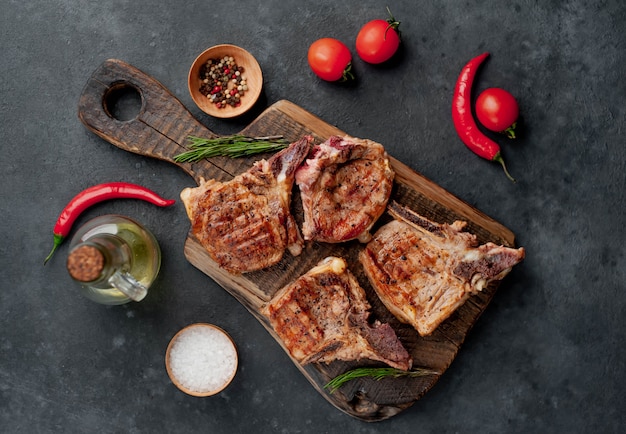 grilled veal steaks on a cutting board with spices on a stone background