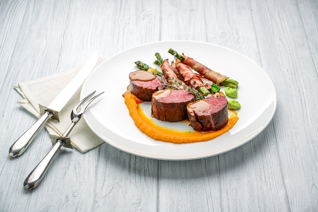 Grilled veal tenderloin with salad, with asparagus and bacon. On the wooden table